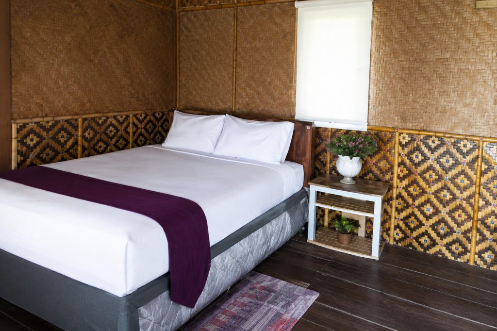 Paket Mandiri Pulau Tidung dengan Kamar penginapan tradisional dengan dinding anyaman bambu, tempat tidur nyaman, dan pencahayaan alami