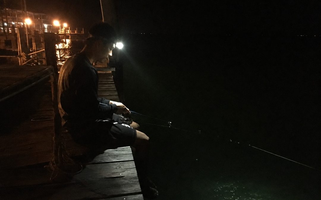 Wisatawan memancing malam hari di dermaga Pulau Tidung dengan lampu sorot